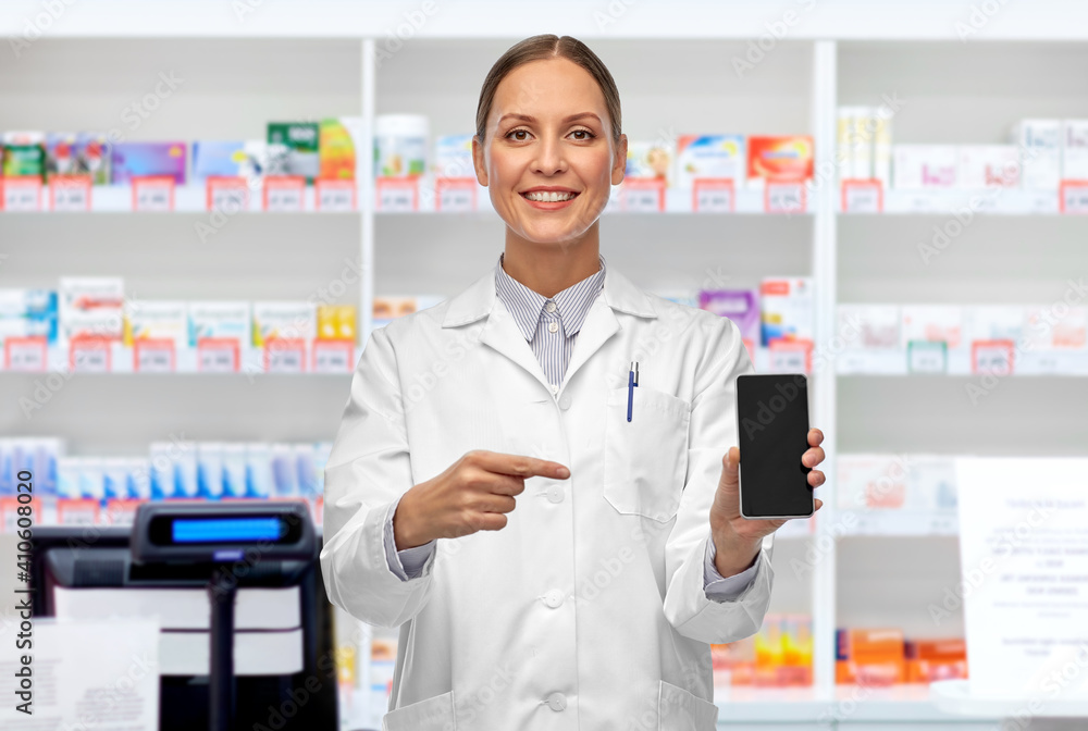 medicine, profession and healthcare concept - happy smiling female doctor or scientist showing smartphone over pharmacy background