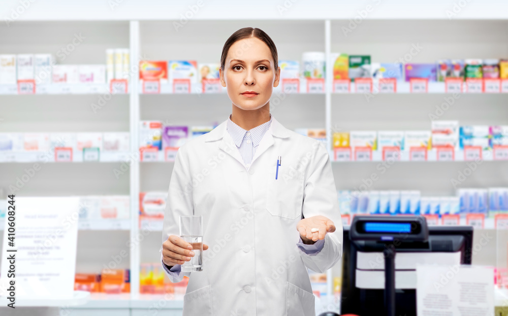 medicine, profession and healthcare concept - female doctor with pill and glass of water over pharmacy background