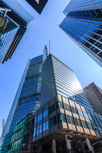 Looking up along high-rise buildings. Blue window facade of commercial buildings in Frankfurt Main. Blue sky in sunny day. Reflections in the glass facade