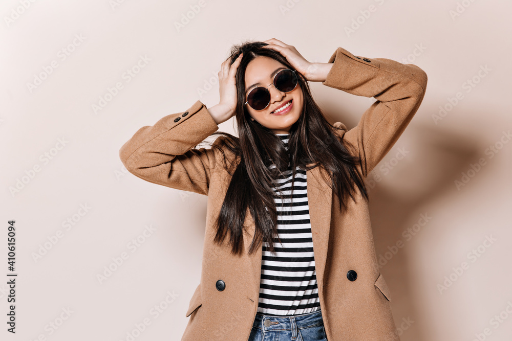 Brunette girl in sunglasses and coat ruffles her hair Brunette girl in sunglasses and coat ruffles her hair
