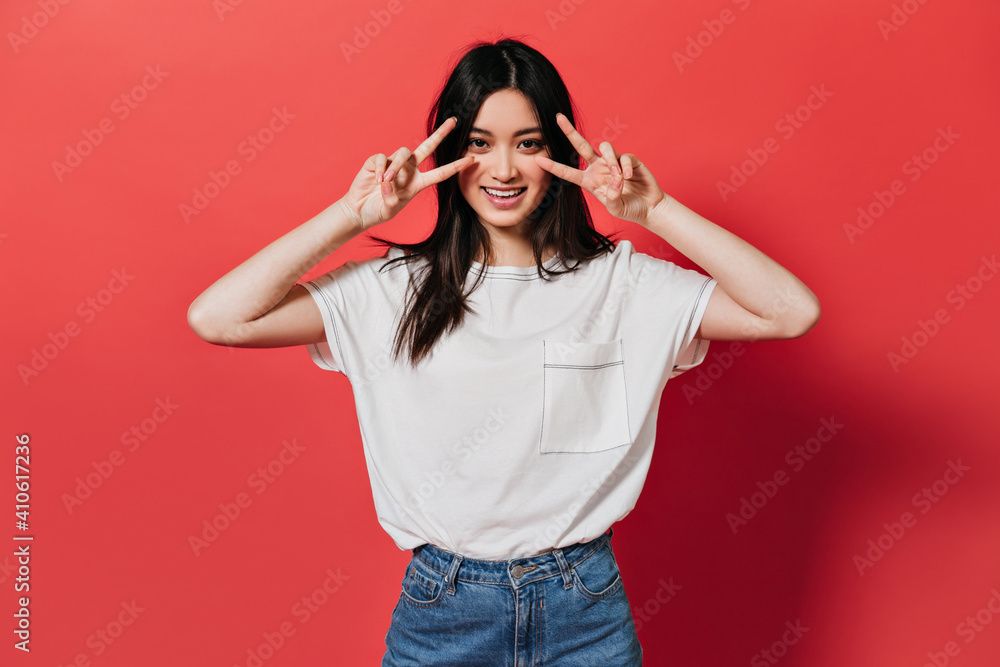 Beautiful girl in white top shows peace sign on isolated background Beautiful girl in white top shows peace sign on isolated background