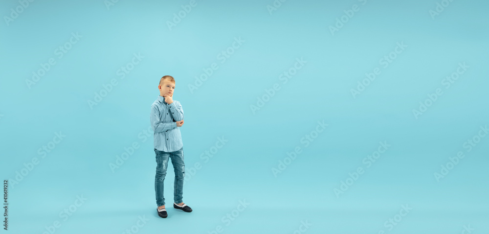 Thoughtful. Childhood and dream about big and famous future. Pretty little boy isolated on blue studio background. Childhood, dreams, imagination, education, facial expression, emotions concept. Flyer Thoughtful. Childhood and dream about big and famous future. Pretty little boy isolated on blue studio background. Childhood, dreams, imagination, education, facial expression, emotions concept. Flyer