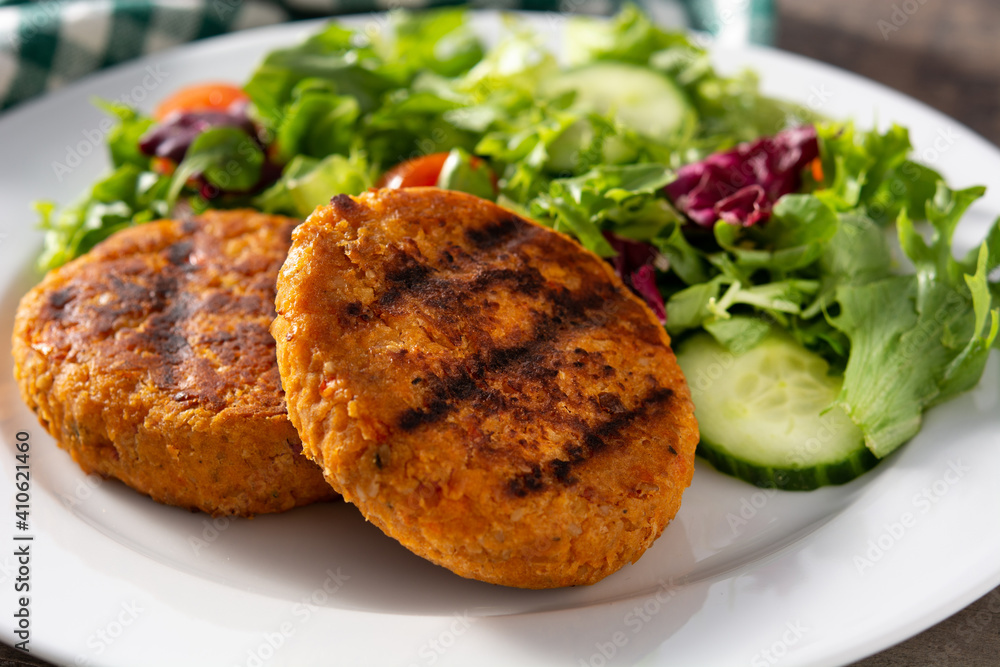 Delicious healthy chickpea burger and salad on wooden table