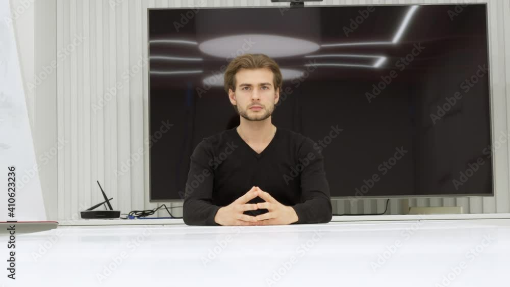 Camera moves up from under table to confident focused man sitting in office conference room looking at camera. Successful Caucasian male employee or CEO posing indoors. Business concept. Camera moves up from under table to confident focused man sitting in office conference room looking at camera. Successful Caucasian male employee or CEO posing indoors. Business concept.