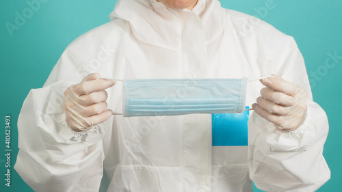 Asian woman in PPE suit ,medical gloves and hloding face mask  or medical mask on green, Tiffany Blue background. photo