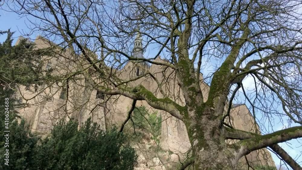 Low angle: Mont Saint-Michel steeple retreating through winter trees Low angle: Mont Saint-Michel steeple retreating through winter trees