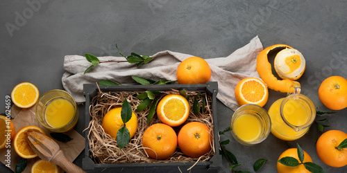 Oranges and juice in grey box on grey background