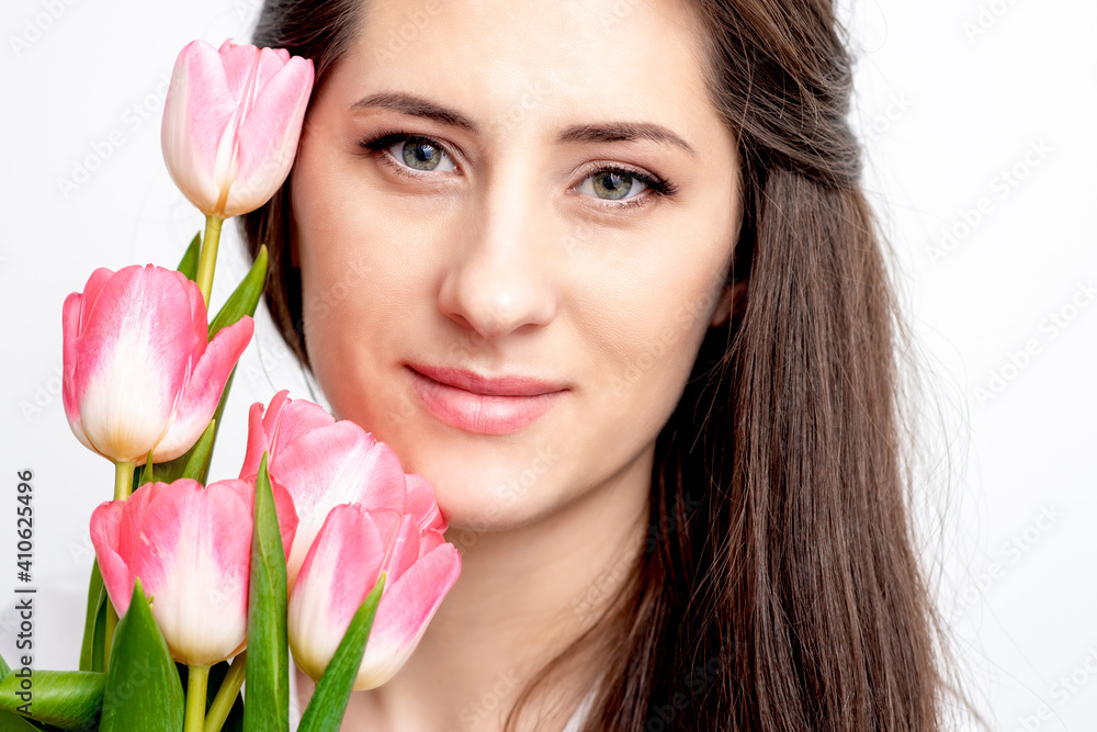Portrait of a happy young caucasian woman with pink tulips against a white background Portrait of a happy young caucasian woman with pink tulips against a white background