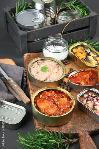 Various canned fish and seafood in aluminum cans. On dark gray background.