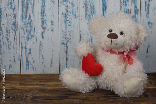 white color bear toy with red heart on wooden floor and light wooden background