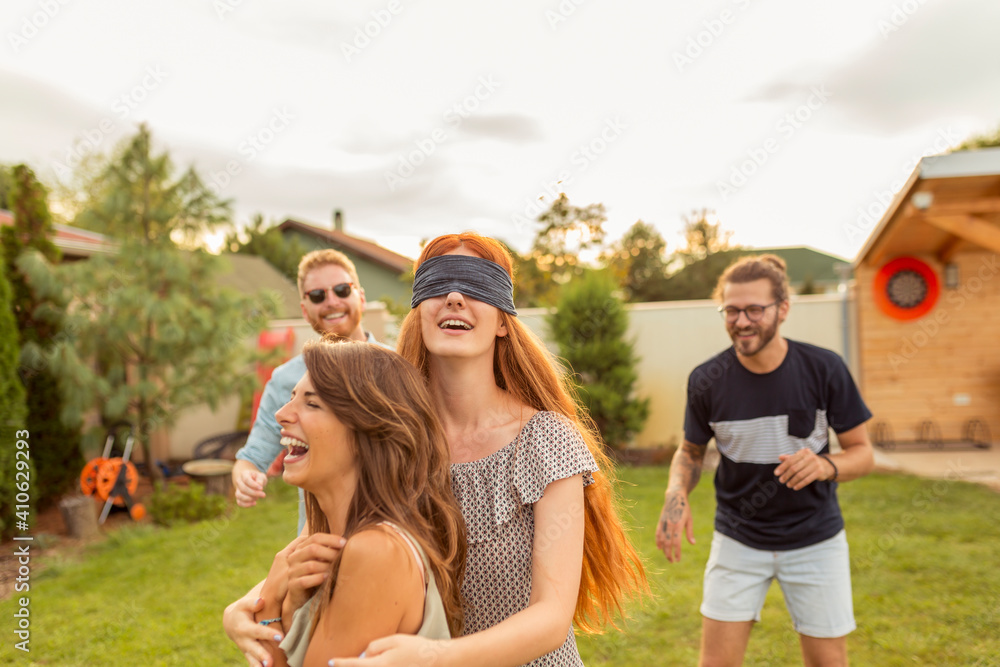 Young friends playing blind man's buff in the backyard Young friends playing blind man's buff in the backyard