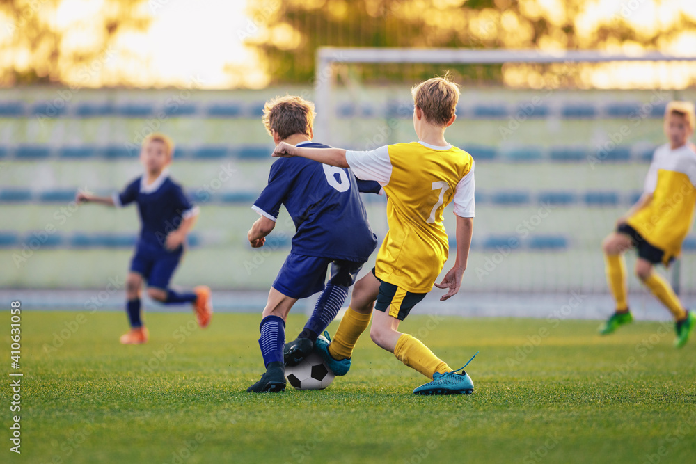 Children Playing Football. Group of Young Boys Kicking Soccer Ball on Stadium Field. Players Compete in Football Match in Two Teams. Kids in Yellow and Blue Soccer Jersey Shirts Children Playing Football. Group of Young Boys Kicking Soccer Ball on Stadium Field. Players Compete in Football Match in Two Teams. Kids in Yellow and Blue Soccer Jersey Shirts