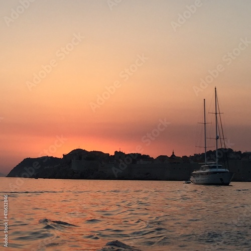 sunset over the sea with yacht and mountains