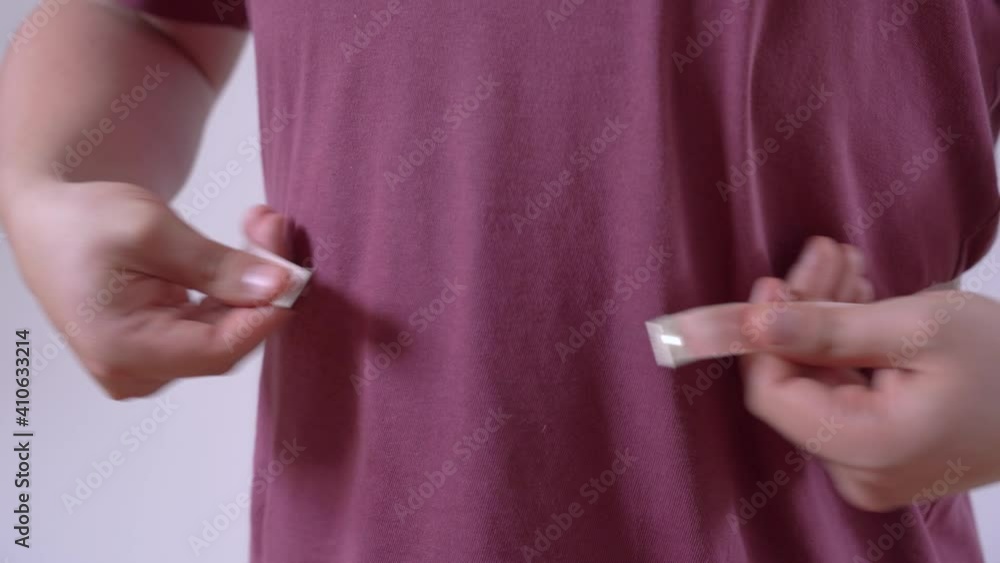 Man with overweight in purple t-shirt tries unfortunately to measure waist with measuring tape after eating hamburger closeup Man with overweight in purple t-shirt tries unfortunately to measure waist with measuring tape after eating hamburger closeup