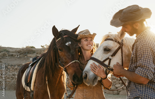 Happy couple having fun with horses inside stable - Young farmers sharing time with animals in corral ranch - Human and animals lifestyle concept © Alessandro Biascioli