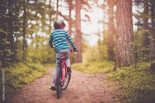 Child on a bicycle in the forest in early morning