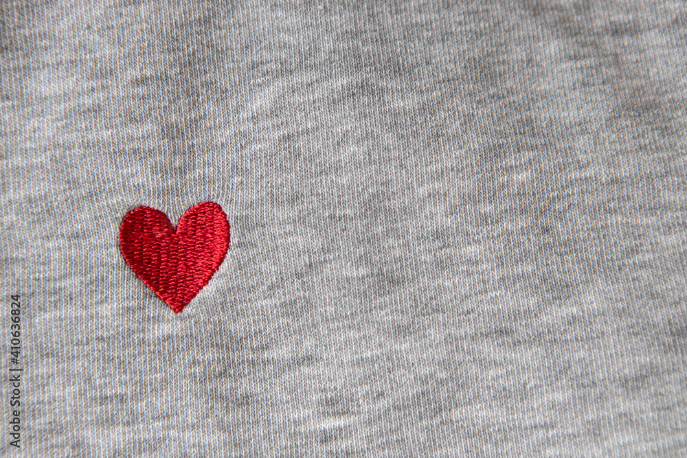 Red heart embroidered with threads on gray fabric background. Close-up, macro, copy space, flat lay. March 8, February 14, birthday, Valentine's, Mother's, Women's day celebration concept, love Red heart embroidered with threads on gray fabric background. Close-up, macro, copy space, flat lay. March 8, February 14, birthday, Valentine's, Mother's, Women's day celebration concept, love