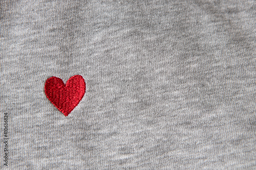 Red heart embroidered with threads on gray fabric background. Close-up, macro, copy space, flat lay. March 8, February 14, birthday, Valentine's, Mother's, Women's day celebration concept, love