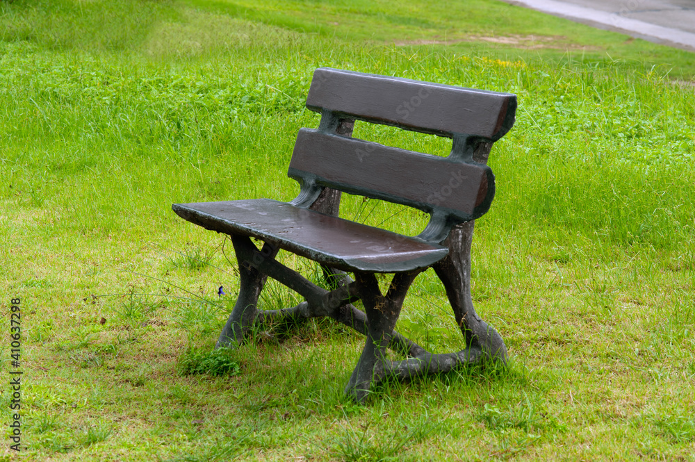 Lonely old concrete cosy bench in a public park area. Lonely old concrete cosy bench in a public park area.