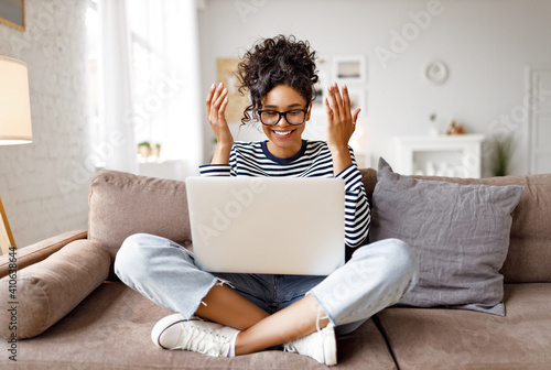 Happy amazed ethnic female making video call on laptop