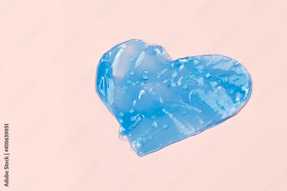 Heart shape from blue cream, gel or toothpaste in pink background.