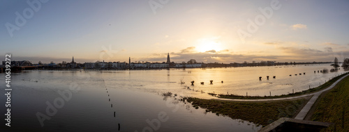 Floodplain landscape with the river IJssel overflowing its boundaries because of high water levels and silhouette cityscape of Zutphen in The Netherlands
