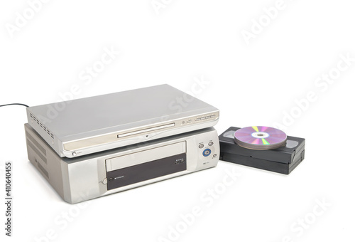 Reproductor de dvd sobre reproductor de vhs junto a cintas de vídeo y cds aislado sobre fondo blanco. Imagen de electrodomésticos en horizontal con espacio de copia. photo