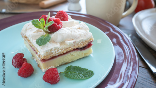 Dessert with fresh raspberries and mint on a plate. Kitchen table. Breakfast. Close-up. Soft focus in the background
