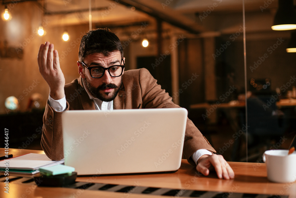 Young businessman working on laptop at office. Businessman sitting at office desk working on new project Young businessman working on laptop at office. Businessman sitting at office desk working on new project