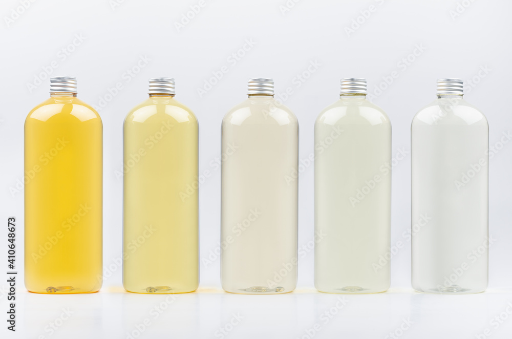 Assortment of plastic tall bottles with cosmetic essential oil of different pastel pale colors, silver cap mockup on white background, template. Assortment of plastic tall bottles with cosmetic essential oil of different pastel pale colors, silver cap mockup on white background, template.