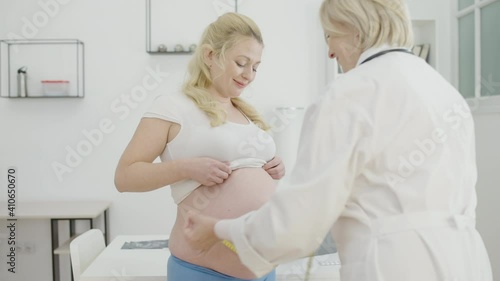Gynecologist examining pregnant belly measuring the size by tape, prenatal care photo