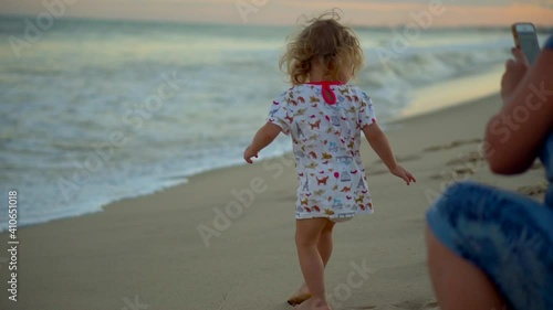 Hammamet, Tunisia 01.21.2021 A girl plays in the sand on the beach by the sea. Children's games with a stick on vacation by the ocean. Happy childhood of a little daughter. High quality FullHD footage photo