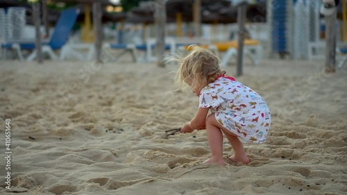 Hammamet, Tunisia 01.21.2021 A girl plays in the sand on the beach by the sea. Children's games with a stick on vacation by the ocean. Happy childhood of a little daughter. High quality FullHD footage photo