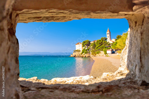 Monastery on pebble beach in Bol view through stone window,