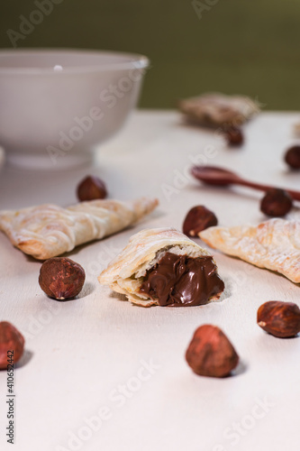 Some nutella hand pies with a wooden spoon and some hazelnu