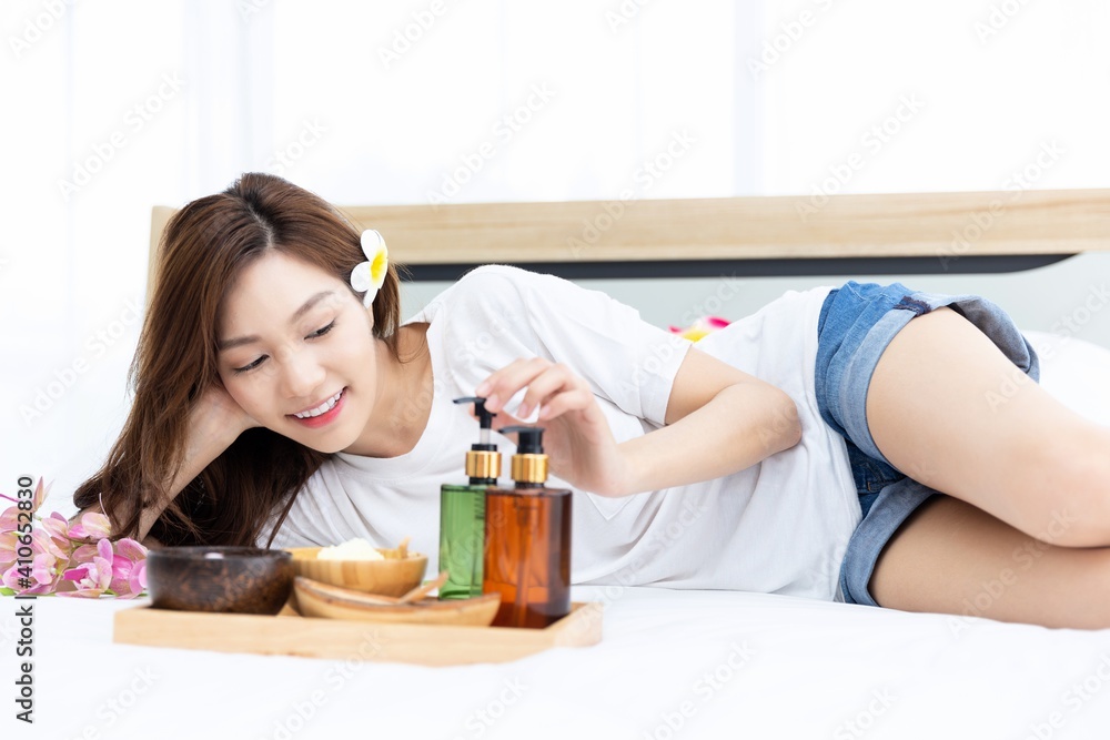 Young Asian women are enjoying the preparation of spa equipment. Smiling young girl waiting for a DIY home spa treatment in her white bedroom. Young Asian women are enjoying the preparation of spa equipment. Smiling young girl waiting for a DIY home spa treatment in her white bedroom.