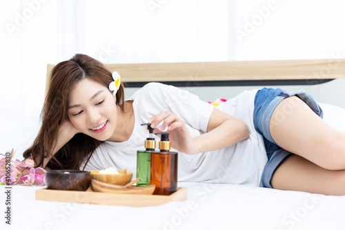 Young Asian women are enjoying the preparation of spa equipment. Smiling young girl waiting for a DIY home spa treatment in her white bedroom.