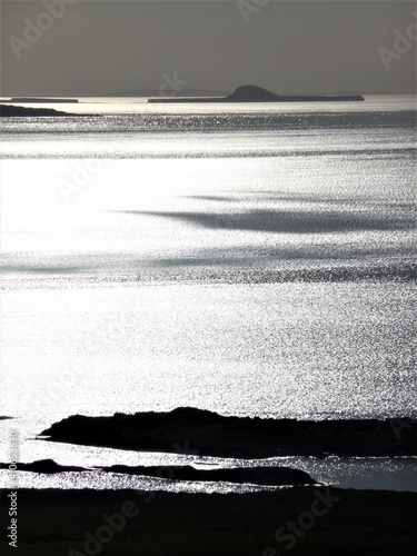 View across a silvery sea to the Treshnish islands and the so-called 'Dutchman's Cap' off the coast of Mull, Scotland  photo