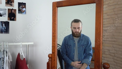 Young Attractive caucasian Man looking into a Mirror Rolling His Sleeves Up