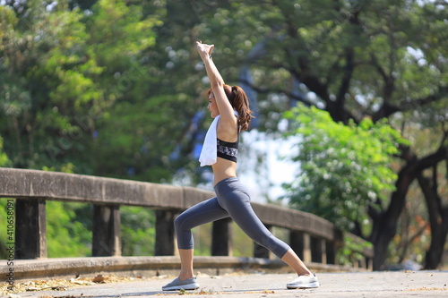 Asian woman in sportswear doing stretching before jogging in the outdoor park with copy space