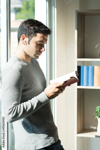 A young businessman working at home and reading by the window
