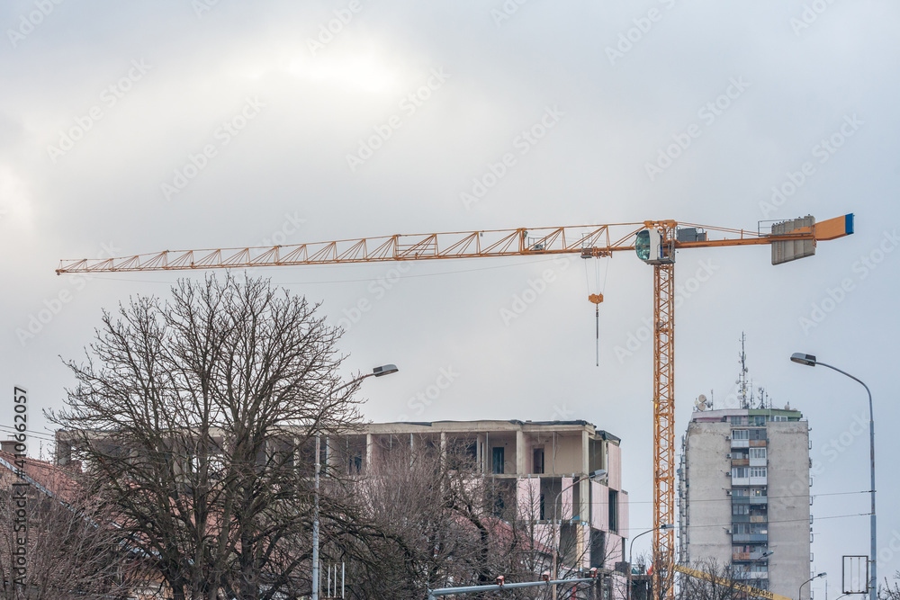 Construction site in Pancevo, Serbia, of a residential building, with scaffholdings, concrete facades and cement blocks, as well as cranes visible, in a real estate development area.