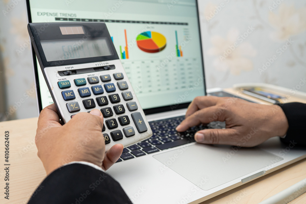 Asian accountant working and analyzing financial reports project accounting with chart graph and calculator in modern office, finance and business concept. Asian accountant working and analyzing financial reports project accounting with chart graph and calculator in modern office, finance and business concept.