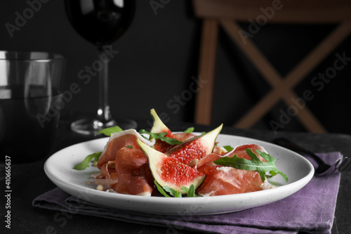 Delicious figs and proscuitto on black table