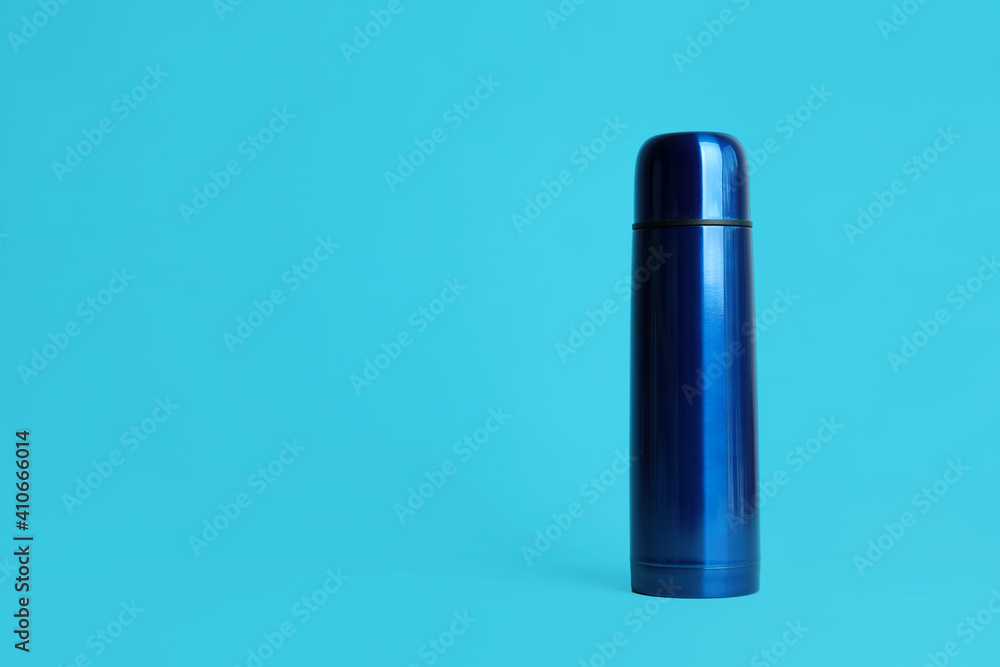 Stylish thermo bottle on light blue background, space for text Stylish thermo bottle on light blue background, space for text