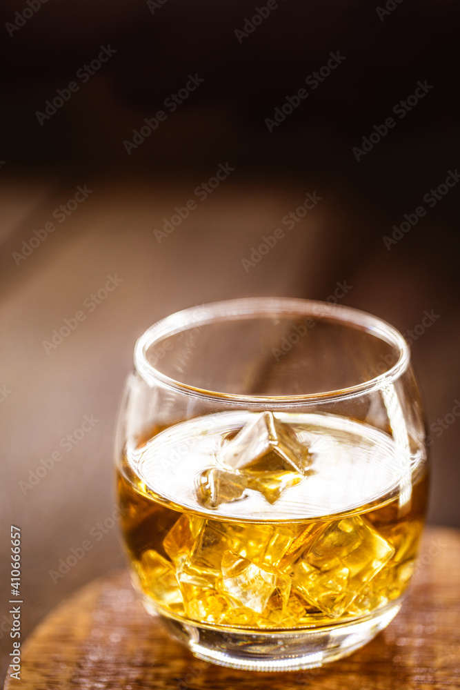 whiskey glass with ice, blurred background and copy space text