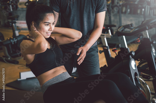 Fotografia Asian woman work out with a personal trainer doing sit ups to stay healthy at the gym