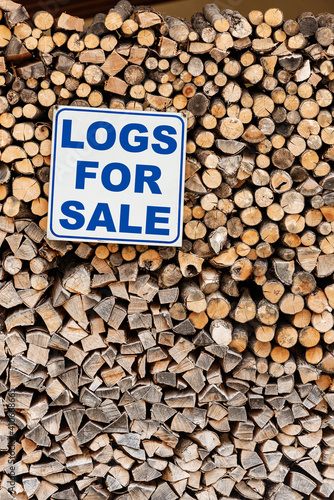 Closeup of a Stack of Firewood with a commercial sign with the short phrase, Logs For Sale, in English language. photo