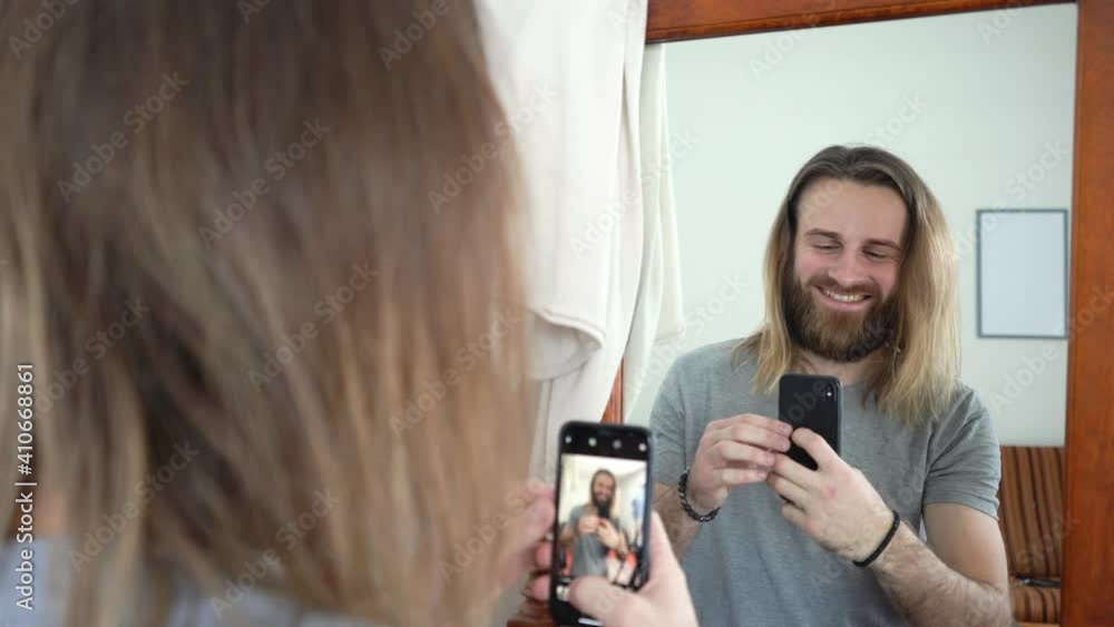 Attractive Young beard man with long hear is looking in a mirror & taking a photo of himself Selfie Attractive Young beard man with long hear is looking in a mirror & taking a photo of himself Selfie