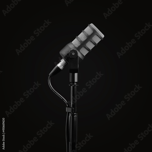 Podcast microphone on a tripod, a black metal dynamic microphone, isolated black background, recording podcast or radio program, show, sound and audio equipment, technology, product photo, side view